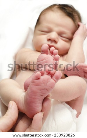 New born baby feet. Hand of the mother holding the sleeping baby boy little foot up.
