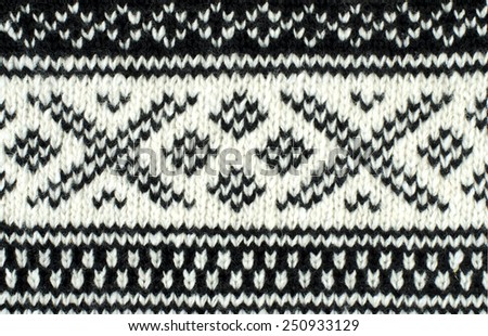 Close up on knit woolen texture. Black and white winter shapes pattern as a background.