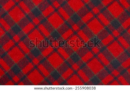 Red and black wool plaid print as background. Rhombus pattern. Scottish tartan pattern.