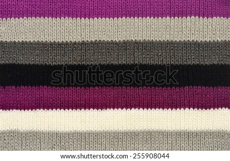 Color stripe wool scarf. Purple with black and white colors stripes on fabric as a background.
