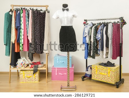Dressing closet with polka dots clothes arranged on hangers. White shirt with bowtie and a black skirt on a mannequin. Colorful wardrobe with clothes and accessories. Girl masculine look.