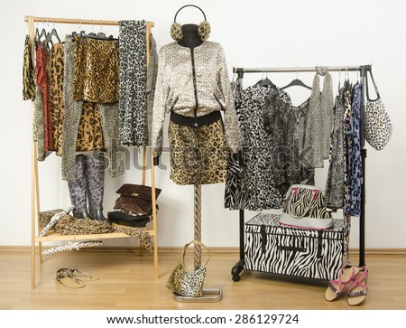 Dressing closet with animal print clothes arranged on hangers. Cheetah print fall outfit on a mannequin. Colorful wardrobe with jungle pattern clothes and accessories.