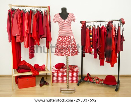 Dressing closet with red clothes arranged on hangers and an outfit on a mannequin.  Wardrobe full of all shades of red clothes, shoes and accessories.
