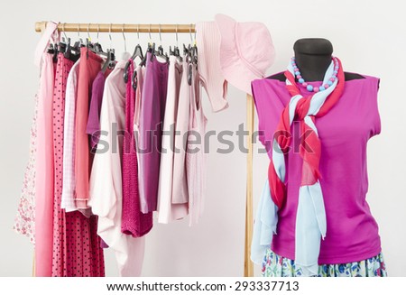 Dressing closet with pink clothes arranged on hangers and an outfit on a mannequin. Wardrobe full of all shades of pink clothes and accessories.