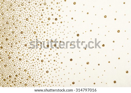 Gold rhinestones on fabric. White fabric decorated with gold jewels as background.