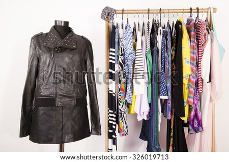 Dressing closet with colorful clothes arranged on hangers and an outfit on a mannequin. Wardrobe with clothes and accessories. Tailor\'s dummy wearing a black leather jacket and skirt.