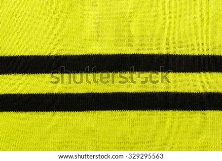 Vibrant green textile pattern as a background. Close up on neon green sweater material texture fabric with two black stripes.
