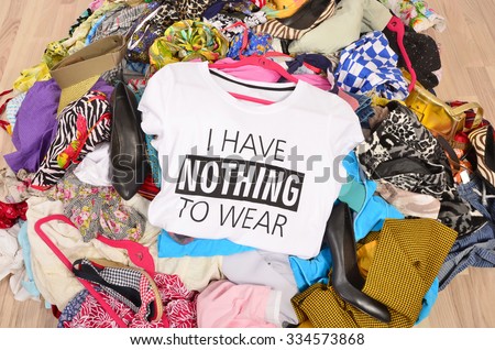 Big pile of clothes thrown on the ground with a t-shirt saying nothing to wear. Close up on a untidy cluttered wardrobe with colorful clothes and accessories, many clothes and nothing to wear.