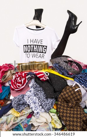Woman legs reaching out from a big pile of clothes with a t-shirt saying nothing to wear. Girl buried under an untidy cluttered wardrobe. Woman in high heels and to much shopping. Shopaholic girl.