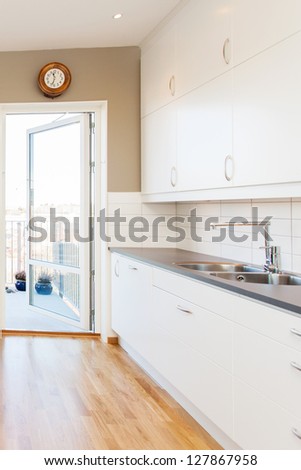 kitchen interior with white cupboards and a open door out to the balcony