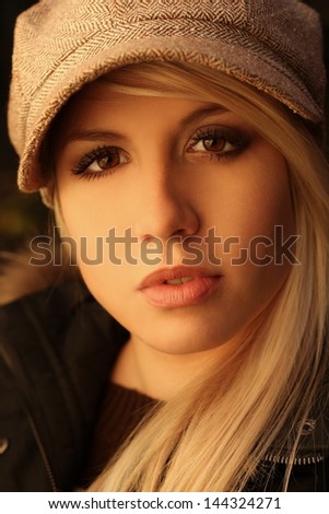 portrait of a beautiful blonde in a sweater and vest and cap in nature, in a forest, fashion photography