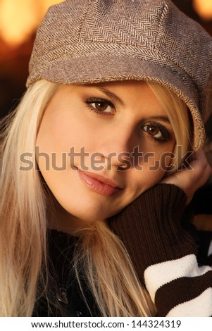portrait of a beautiful blonde in a sweater and vest and cap in nature, in a forest, fashion photography