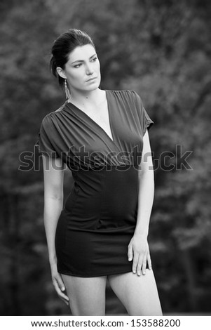 Beautiful brunette in a dress posing on a golf course, in a nature,  fashion photography, black and white photo
