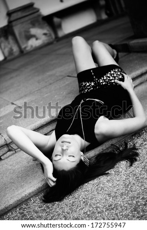 Beautiful brunette in a black shirt and skirt lying on the stairs, fashion photography, black and white photo