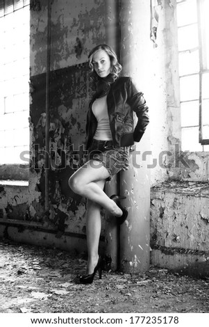 Beautiful brunette in a white shirt, jacket and denim skirt posing in a old building, fashion photography, black and white photo