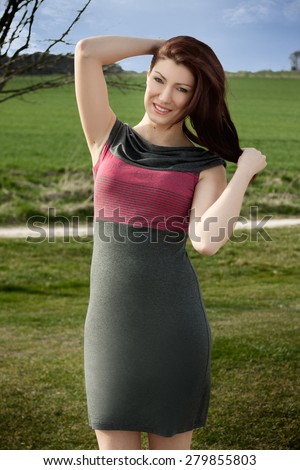 Beautiful brunette is posing on a golf course. She is wearing a dress. Fashion photography.