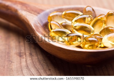 Cod liver oil omega 3 gel capsules isolated on wooden background
