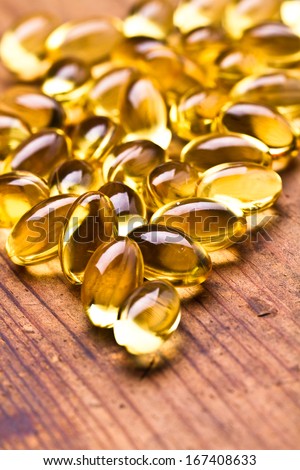 Cod liver oil omega 3 gel capsules isolated on wooden background