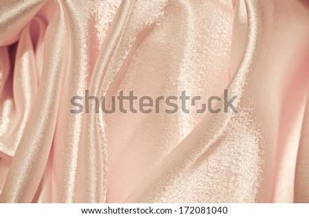 Chaotic drapery of delicate pink satin. pastel satin texture