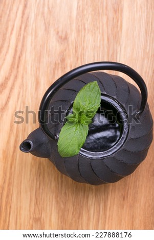 Cast iron teapot and mint leaves on old stones table.