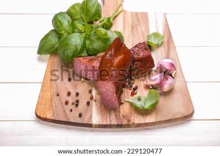 Natural prepared slow food. Smoked pork sirloin with herbs and spices on wooden board. Traditional Polish cold meats