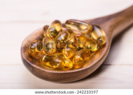 Cod liver oil omega 3 gel capsules isolated on wooden background. Vitamin D capsuls.  dietary supplement