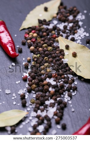 Assorted spices on a black stone background, sea salt, black pepper, red chilli