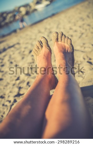 Vintage photo of foot of tanning man lying on beach