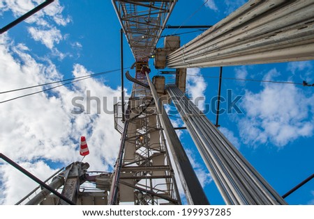 Oil drilling rig against a blue sky with clouds