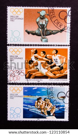 DDR - CIRCA 1980: A stamp printed in DDR shows sportsmen who jump,run and swim, circa 1980.