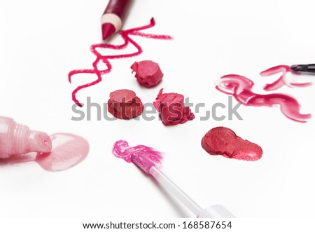 Different tones of lip gloss, lipstick and lip liner on light background, side view