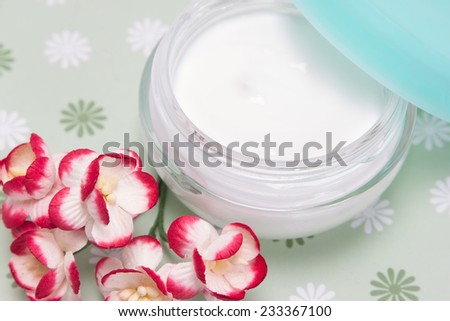 Open jar of cream with cherry blossoms closeup. Shallow depth of field