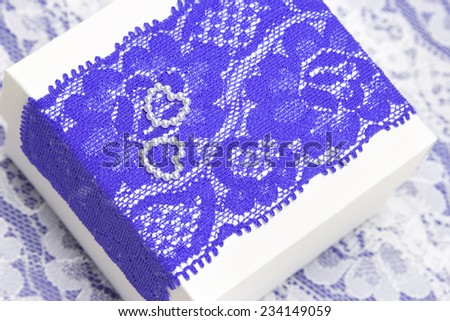 Wedding gift: white gift box decorated with violet lace and two small hearts made of beads. Shallow depth of field