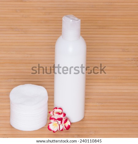 Facial cleaning and makeup removing cosmetic product with  cotton pads and small flowers on wooden surface