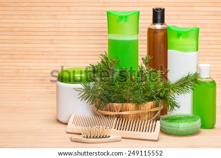 Natural hair care cosmetics and accessories: wooden basket with pine branches, shampoo, conditioner, balm, mask, sea salt, wooden combs