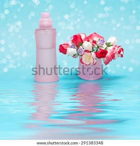 Close-up of perfume bottle with bouquet of flowers in its cap reflected in the water surface. Cool and floral fragrance concept