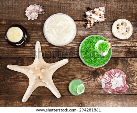 Spa cosmetics and accessories: sea salt, loofah, skin care cream, natural scrubs with shells and starfish on wooden planks. Top view. High contrast