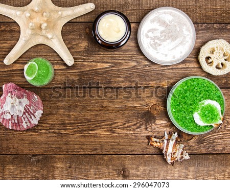 Spa cosmetics and accessories: sea salt, loofah, skin care cream, natural scrubs with shells and starfish on wooden planks. Top view. Frame, copy space