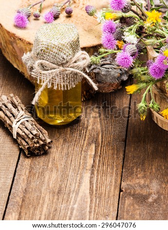 Bottle filled with fresh, raw honey and bouquet of wildflowers in ligneous basket on wooden planks