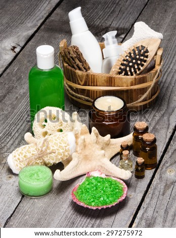 Spa cosmetics and accessories: sea salt in shell, wisp of bast, loofah, skin care creams, natural honey and lemongrass scrub, essential oils, shower gel, comb, pumice with starfish on wooden planks