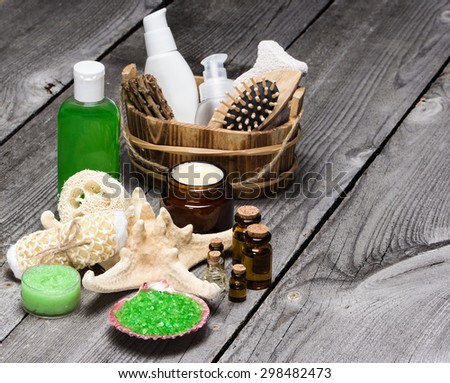 Spa cosmetics and accessories: sea salt in shell, wisp of bast, loofah, skin care creams, natural honey scrub, essential oils, shower gel, comb, pumice with starfish on wooden planks. Copy space