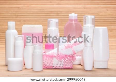 Big collection of cosmetic products for skincare with a charming wicker basket and towel on wooden surface. White and pink colors