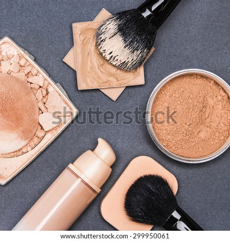 Set of makeup products to even out skin tone and complexion: concealer, corrector, open cream foundation bottle, jar of loose powder, crushed compact powder with makeup brushes and cosmetic sponge