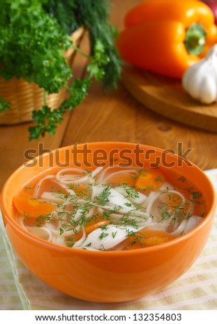 Homemade chicken soup with noodles in the orange bowl.