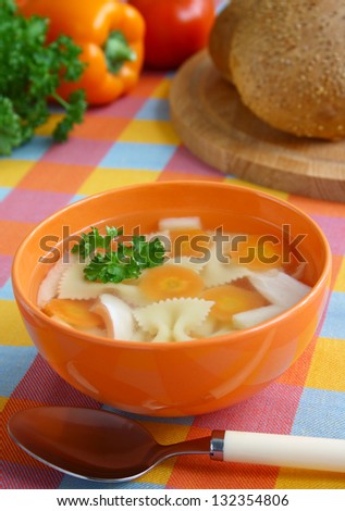 ?hicken soup with farfalie in the orange bowl.