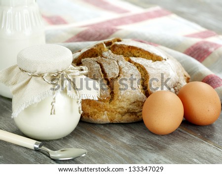 Bread, milk, eggs and  yogurt on a wooden table