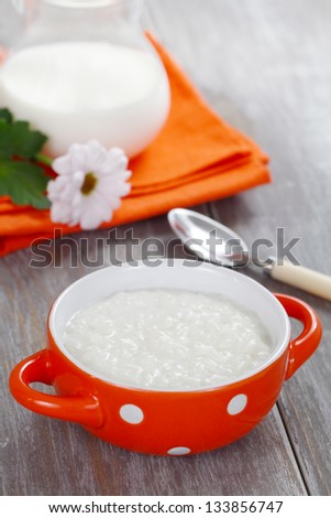 Rice porridge in the orange bowl on wooden table