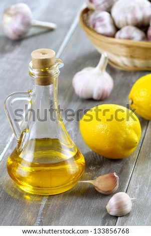 Olive oil, lemon and garlic in a basket on a wooden table.