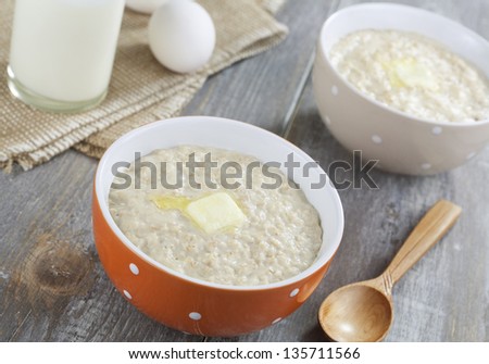 Oatmeal porridge with butter, milk and eggs on a wooden table