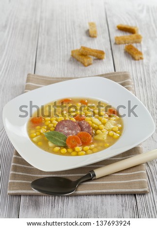 Pea soup with smoked sausage in a square plate on the table